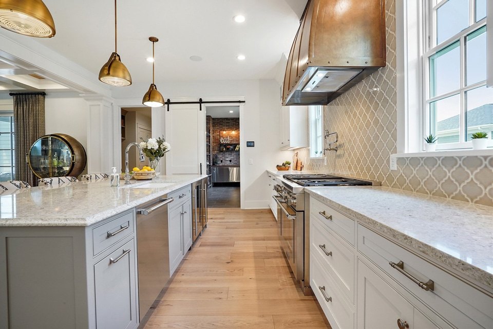 Light countertops along a gray kitchen with a copper range hood